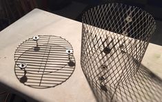 a wire basket sitting on top of a table next to a metal object with holes in it