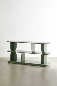 a green table sitting on top of a cement floor next to a white wall in an empty room