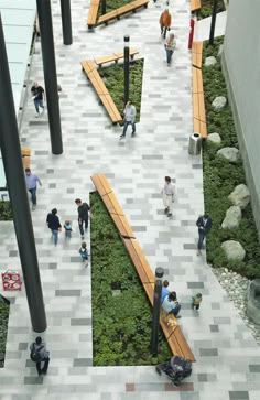 people are walking around in an open area with grass growing on the floor and wooden benches