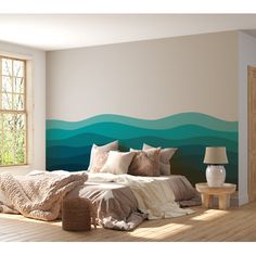 a bedroom with a large bed in front of a wall painted with blue and green waves