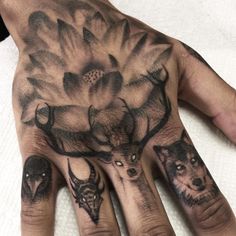 a person's hand with tattoos on it and two deer heads in the middle