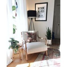 a white chair sitting on top of a hard wood floor next to a potted plant