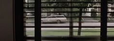 an old car is seen through the window blinds