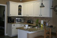 a kitchen with white cabinets and granite counter tops