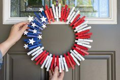 a wreath made out of red, white and blue clothes pins is being held by someone's hand