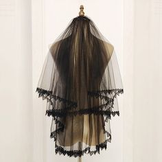 a veil hanging on a hook in front of a white door with black lace trim