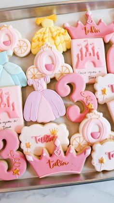 decorated cookies in the shape of princess's tiaras and dresses on a tray