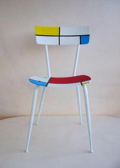 a white chair with red, blue, yellow and black stripes on it's seat