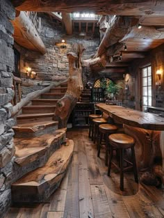 the interior of a rustic log cabin with wood flooring and wooden stairs leading up to an upper level bar area