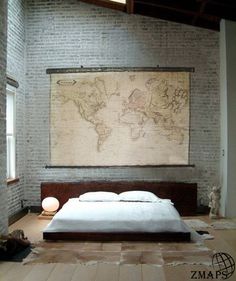 a large map hanging on the wall above a bed in a room with brick walls