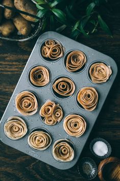 cupcakes in a muffin tin on a wooden table next to some potatoes