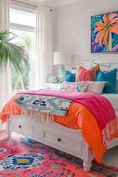 a white bed with bright colored pillows and blankets on top of it in a bedroom