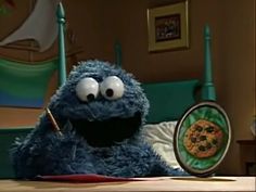 the cookie monster is sitting on his bed and holding a pen in front of him