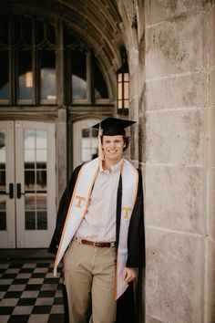 a man wearing a cap and gown standing in front of a building with a black and white checkered floor