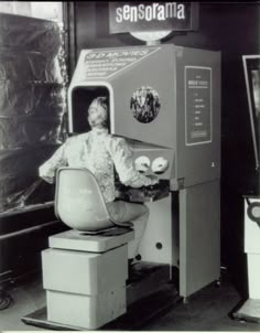 an old photo of a person sitting on a chair in front of a machine