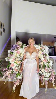 a woman in a white dress standing next to flowers