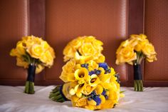 a bouquet of yellow flowers sitting on top of a white bed next to two vases