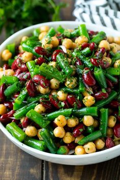 a white bowl filled with green beans and other vegetables on top of a wooden table