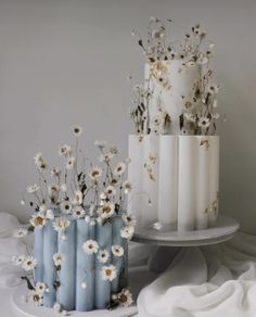 three tiered cakes with flowers on them sitting on a table next to each other