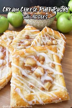 four pieces of apple cream cheese puff pastry on a cutting board with apples in the background