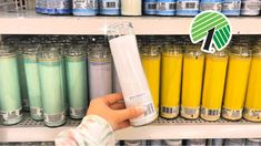 a person is holding up a tube of liquid in front of some shelves with different colored liquids