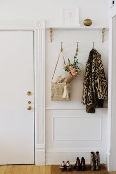 a coat rack with two coats hanging from it's hooks and flowers in a basket