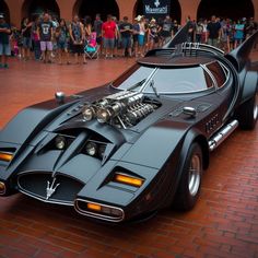 a black batmobile parked in front of a crowd