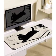 a computer desk with a black cat on it's side and a monitor screen