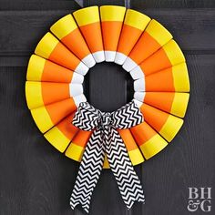 an orange and yellow wreath hanging on the front door with black and white chevron ribbon