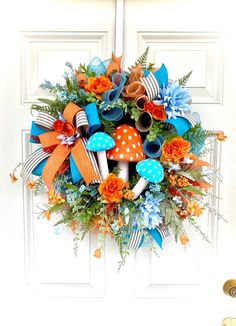 a wreath with orange, blue and white flowers on it is hanging on the front door