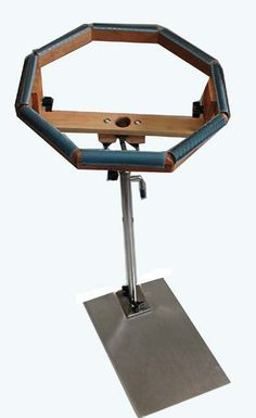 a metal and wood stand with a blue seat on it's legs, holding a wooden object