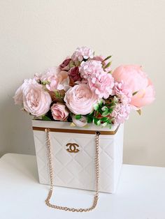 pink flowers in a chandelier bag on a white table with a gold chain