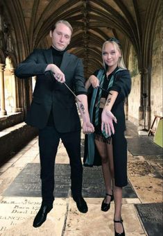 a man and woman standing next to each other in an old building with stone floors