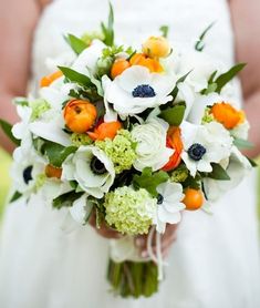 a bridal holding a bouquet of white and orange flowers on her wedding day,