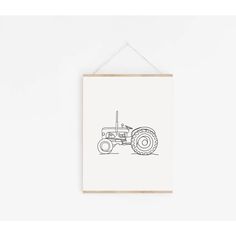 a black and white drawing of a tractor hanging from a wooden frame on a wall