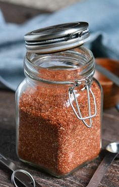 a glass jar filled with red sand next to spoons