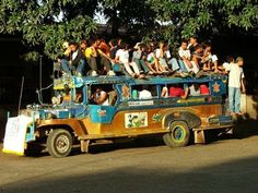 a group of people riding on the back of an old bus in front of some trees