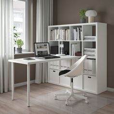 a white desk sitting in front of a window next to a book shelf filled with books