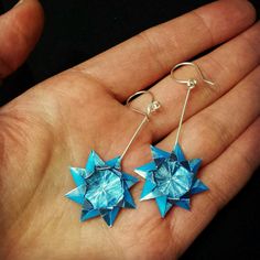 a pair of blue origami stars are held in someone's hand,