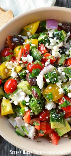 greek salad in a white bowl with feta cheese and olives on the side