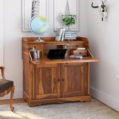 a desk with a laptop on top of it next to a chair and wall hangings