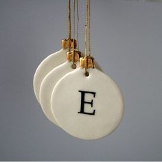 three white ceramic ornaments with black letters hanging from strings in the shape of letter e