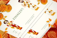 an image of two wedding cards on top of some orange flowers and greenery in the background