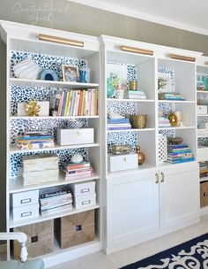 a white bookcase filled with lots of books next to a blue and white rug