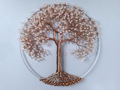 a tree with white flowers on it is in a circular glass plate, hanging from the wall