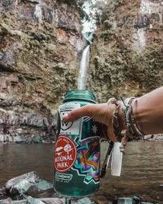 a person holding a water bottle in front of a waterfall