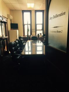 a conference room with black leather chairs and a large sign on the wall above it