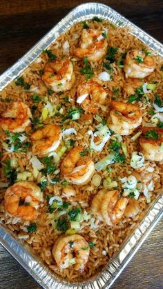 a pan filled with shrimp and rice on top of a wooden table