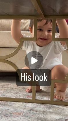 a baby is sitting on the floor and looking through a window that says his look