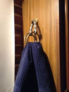 a towel is hanging on a hook in a wooden door with a blue towel draped over it